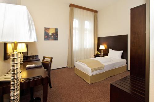 a hotel room with a bed and a desk at Grand Palace Hotel Hannover in Hannover
