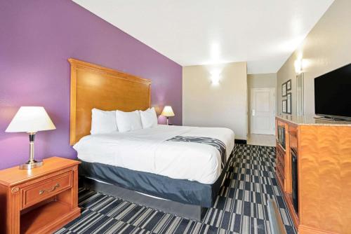 a hotel room with a bed and a flat screen tv at La Quinta by Wyndham Ada in Ada