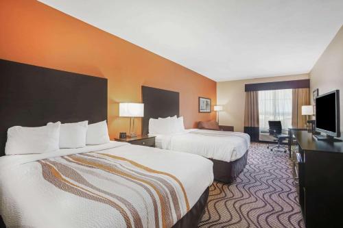 a hotel room with two beds and a flat screen tv at La Quinta by Wyndham Beeville in Beeville