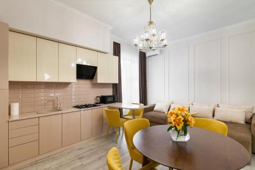 a kitchen and living room with a table and yellow chairs at Avangard DeLuxe Art Apart in Lviv