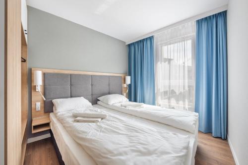- une chambre avec 2 lits et une fenêtre avec des rideaux bleus dans l'établissement Apartamenty Sun & Snow Bel Mare, à Międzyzdroje