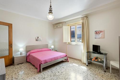 a bedroom with a pink bed and a television at Tra il Centro e il Mare Apartment con terrazzo in Aci Castello
