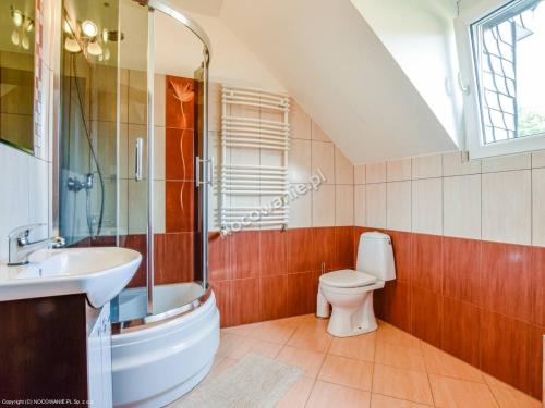 ein Bad mit einem Waschbecken, einem WC und einem Fenster in der Unterkunft Willa Architekt in Karpacz