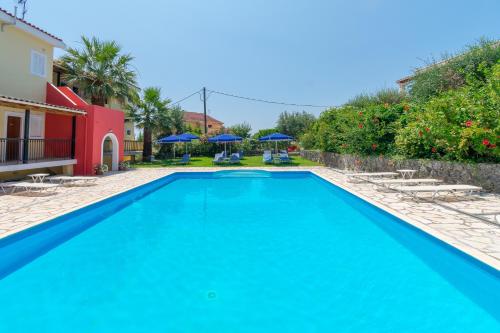 a pool with chairs and umbrellas next to a house at Elite Corfu - Adults Friendly in Kommeno