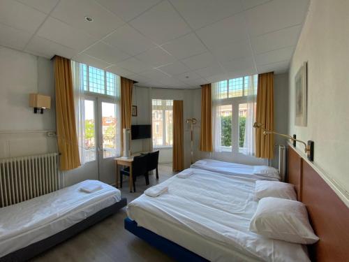 a bedroom with three beds and a desk and windows at CoronaZeist-Utrecht NL in Zeist