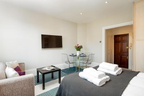 a living room with a bed and a couch and a table at CAPITAL Sloane Street Studio with Balcony in London