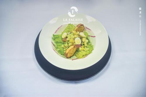 a plate of food with a salad on a table at Hotel La Falaise Bonapriso in Douala