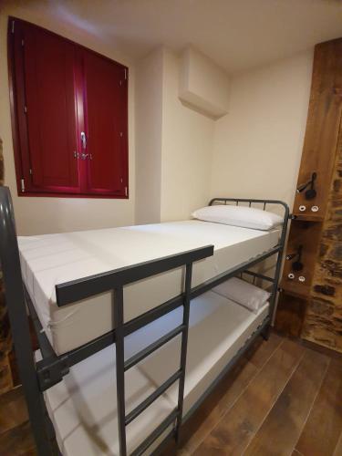 two bunk beds in a room with red cabinets at Albergue Casa Cuartel in Fonsagrada