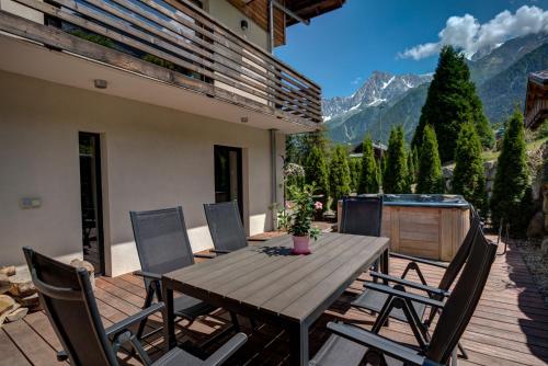a wooden table and chairs on a patio with mountains at Chalet Rubicon in Les Houches
