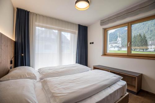 two beds in a room with a window at App. Col Toronn - Ciasa Lavarella in San Vigilio Di Marebbe