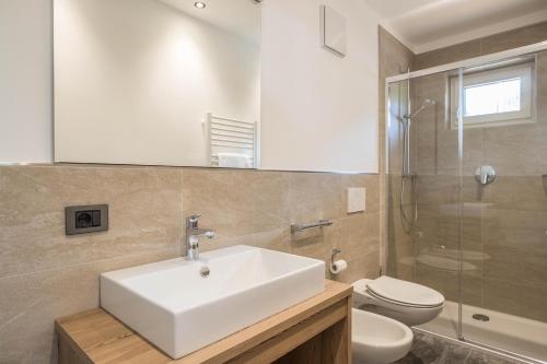 La salle de bains est pourvue d'un lavabo blanc et de toilettes. dans l'établissement App. Col Toronn - Ciasa Lavarella, à San Vigilio Di Marebbe