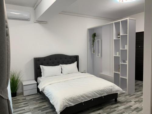 a white bedroom with a bed with a black headboard at Apartament Alexandra in Mamaia