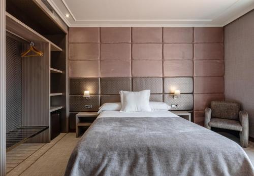 een slaapkamer met een groot bed en een stoel bij Hotel Pensua Punta del Este in Carballo