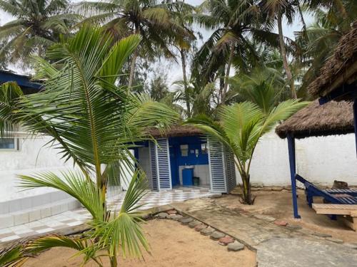 a house with palm trees in front of a building at Hotel La Madrague in Grand-Bassam
