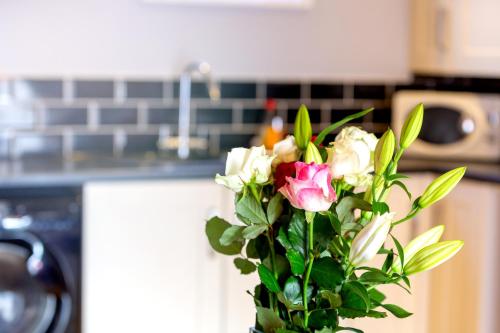 a bouquet of roses in a vase in a kitchen at Church View Apartments in Weymouth