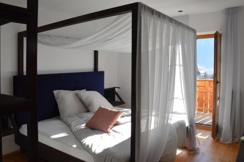 a bedroom with a canopy bed and a balcony at Apartment Pyrus in Tirolo