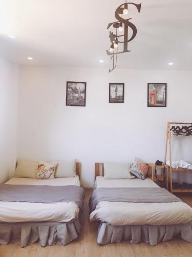 two beds in a room with white walls and a chandelier at Sele House in Ha Tien
