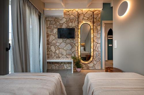 a bedroom with two beds and a stone wall at Horizon Apartments - Beachfront Luxury, by ZanteWize in Laganas