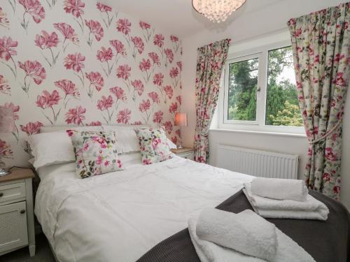 a bedroom with a bed with pink floral wallpaper at Hunters Cottage in Highpeak Junction