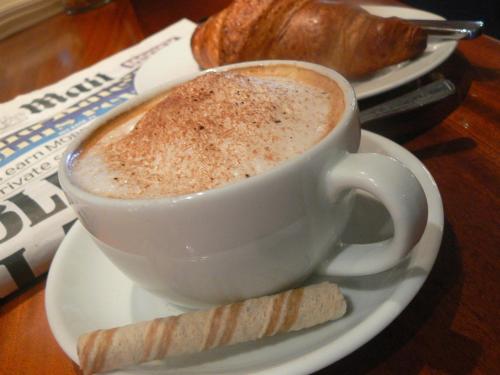 una taza de café y un trozo de pan en un plato en The Walnut Tree Inn Mere, en Mere