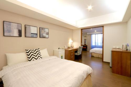 a hotel room with a bed and a desk and a bedroom at Sky19 Hotel in Taipei