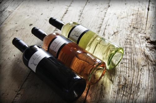 three bottles of wine sitting on a wooden table at Apartments Galumbo - bleiben & genießen in Illmitz