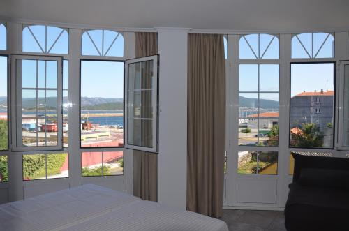 1 dormitorio con ventanas y 1 cama con vistas en Pensión o noso bar, en Portosín