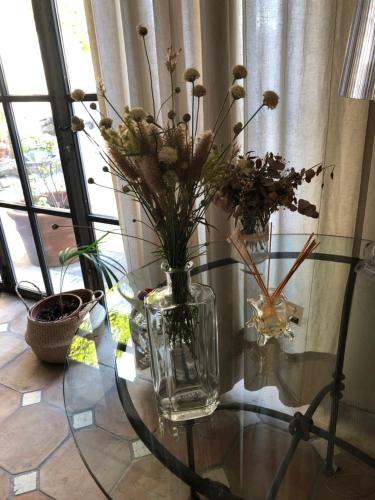 a glass vase with flowers on a glass table at Le Colombier in Sablet