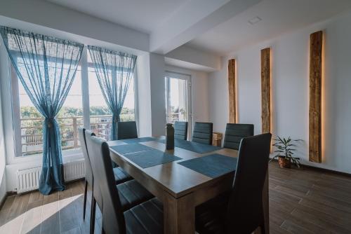 a dining room with a table and chairs and a large window at Sunset Inn in Sîngeorgiu de Mureş