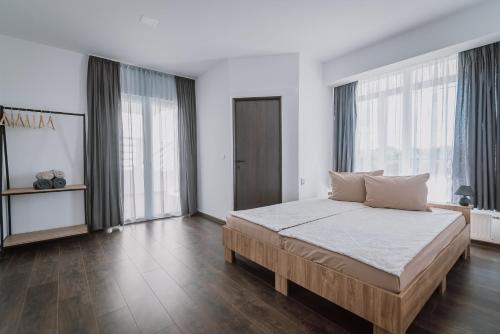 sypialnia z dużym łóżkiem i dużymi oknami w obiekcie Sunset Inn w mieście Sângeorgiu de Mureș