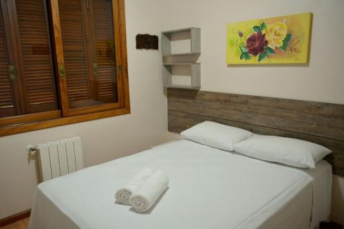 Un dormitorio con una cama blanca con una toalla. en LOCAR-IN GRAMADO - Residencial Maranello, en Gramado