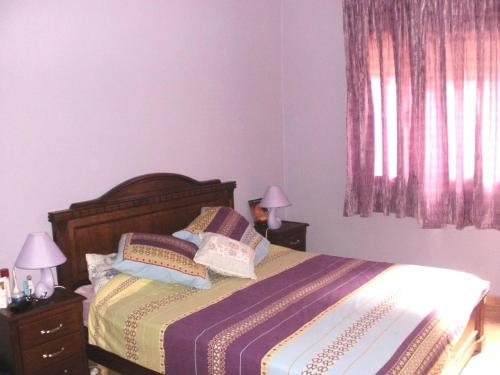 a bedroom with a bed with two lamps and a window at Appartement high standing piscine jardin mer proche Mohammedia in Figuiq
