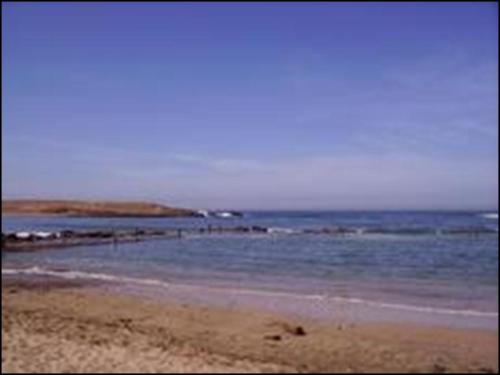 a beach with the ocean and rocks in the water at Appartement high standing piscine jardin mer proche Mohammedia in Figuiq