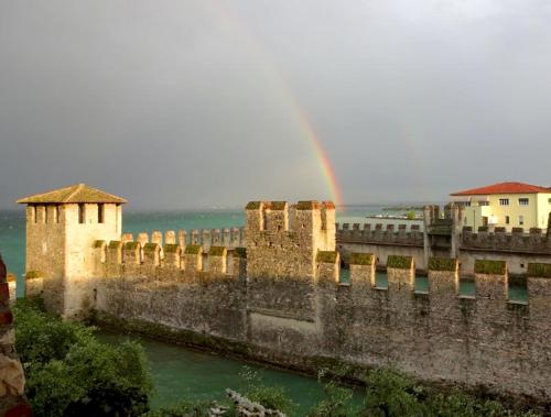 a rainbow over an old castle and a river at Hotel Grifone in Sirmione