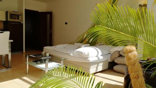 a living room with a white bed and a palm tree at Apartmány Duo in Dačice
