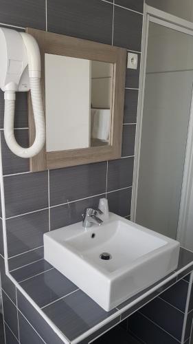 a bathroom with a white sink and a mirror at Hotel Cosmos in Paris
