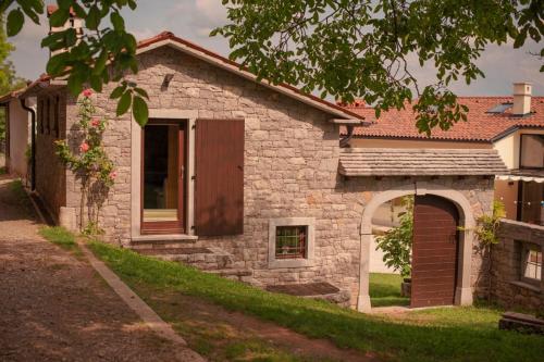 a stone house with a door and a window at Tmbin's barn - nature, horses, family in Sežana