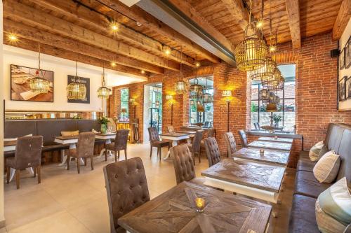 a restaurant with tables and chairs and a brick wall at Hotel Achterum Greetsiel in Greetsiel
