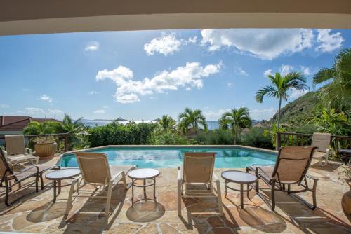 a swimming pool with chairs and a table next to a pool at LOBLOLLY in Virgin Gorda