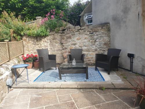 a patio with chairs and a table and a stone wall at Sherwood House in Matlock