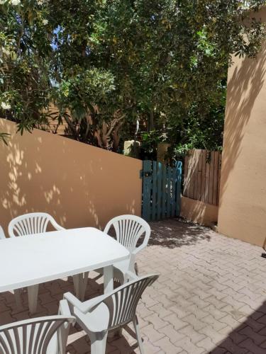 une table et des chaises blanches sur un patio arboré dans l'établissement APPARTEMENT T1, à Hyères