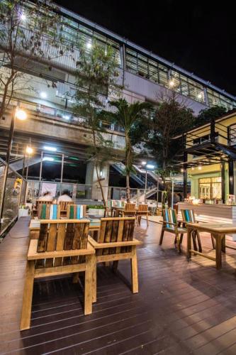 a group of wooden benches on a patio at night at NTY Hostel Near Suvarnabhumi Airport in Bangkok