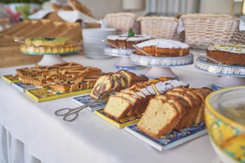 a table topped with different types of cakes and pastries at Villa Sant'Andrea, A Belmond Hotel, Taormina Mare in Taormina