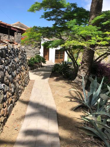 a walkway leading to a white building with a stone wall at Casas Rurales Hermigua in Hermigua