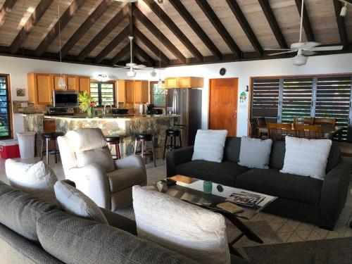 a living room with two couches and a kitchen at VILLA VALMARC in Virgin Gorda