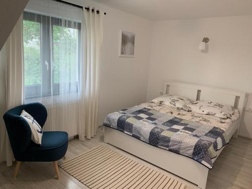 a bedroom with a bed and a chair and a window at Apartamenty Wydminy in Wydminy