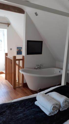 a bathroom with a tub and a tv on the wall at The New Inn in Cerne Abbas
