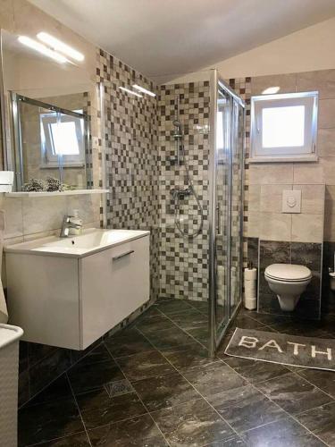 a bathroom with a sink and a shower and a toilet at Apartman Laura in Tribunj