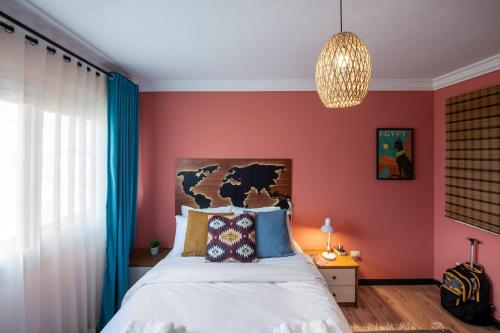 Un dormitorio con una cama con paredes rojas y una lámpara de araña. en Two Swings & A Pool - 5 min to Airport, en El Cairo