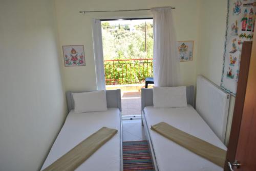 two beds in a room with a window at Monika Lefkada in Tsoukaladhes